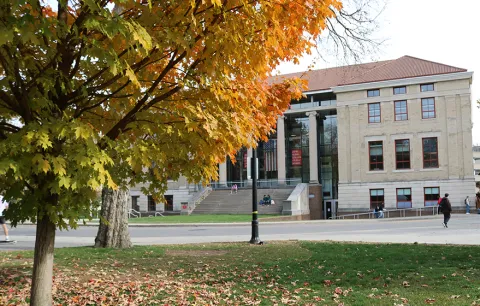the outside of Page Hall, the home of Ohio State’s John Glenn College of Public Affairs, with a fall tree in the foreground