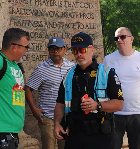 Columbus Dialogue Team members, Sgt. Steve Dyer, center, and Officer E.H. Ortega, far right, to the leader of preachers demonstrating at the Pride March while Ohio State’s Glenn College Professors Russell Hassan, back left, and Cliff Stott look on.