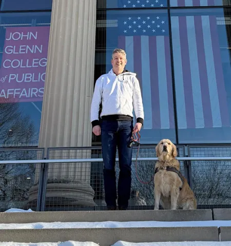 John Glenn College of Public Affairs graduate Ryan Brownfield and his dog, Mable, stand on the steps in front of Page Hall.