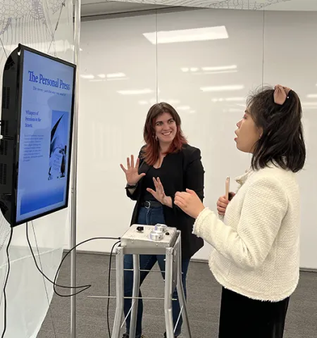 Glenn College graduate Susannah Montgomery, left, and undergraduate statistics student Carol Luo, select inputs using dials and watch as generative AI changes the tone and bias of a news article. (Credit: Joan Slattery Wall)