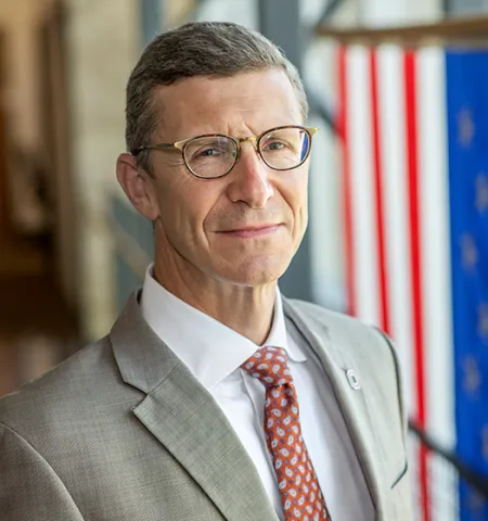 Dean Trevor Brown of the John Glenn College of Public Affairs with an American Flag behind him.