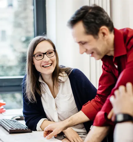 A professional woman sitting and smiling at her male colleague (Source Getty Images).