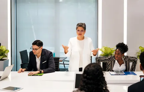 a leader standing and speaking to a table of team members