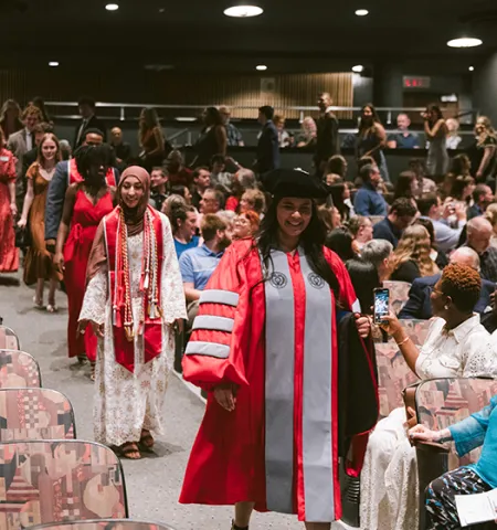 Spring 2026 graduates from Ohio State’s John Glenn College of Public Affairs proceed into the pre-commencement ceremony watched by family and friends.