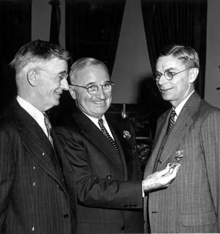 two men admire an honorary medal on another's lapel